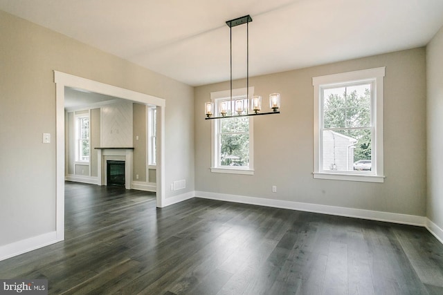 unfurnished dining area with dark hardwood / wood-style floors, a high end fireplace, and a chandelier