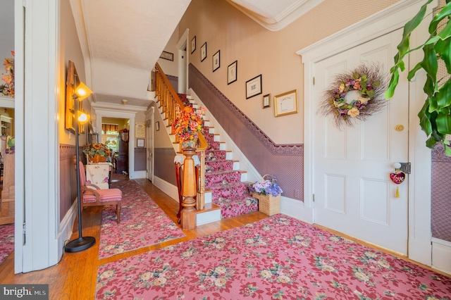 foyer with wood-type flooring and crown molding