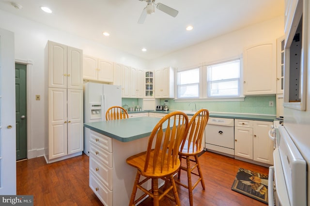 kitchen featuring ceiling fan, a center island, white appliances, a breakfast bar, and white cabinets