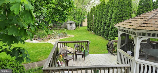 deck featuring a lawn, a gazebo, and a storage shed