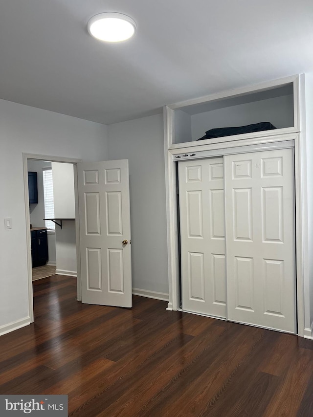 unfurnished bedroom with a closet and dark wood-type flooring