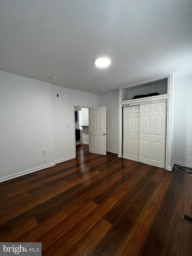 unfurnished bedroom featuring dark wood-type flooring and a closet