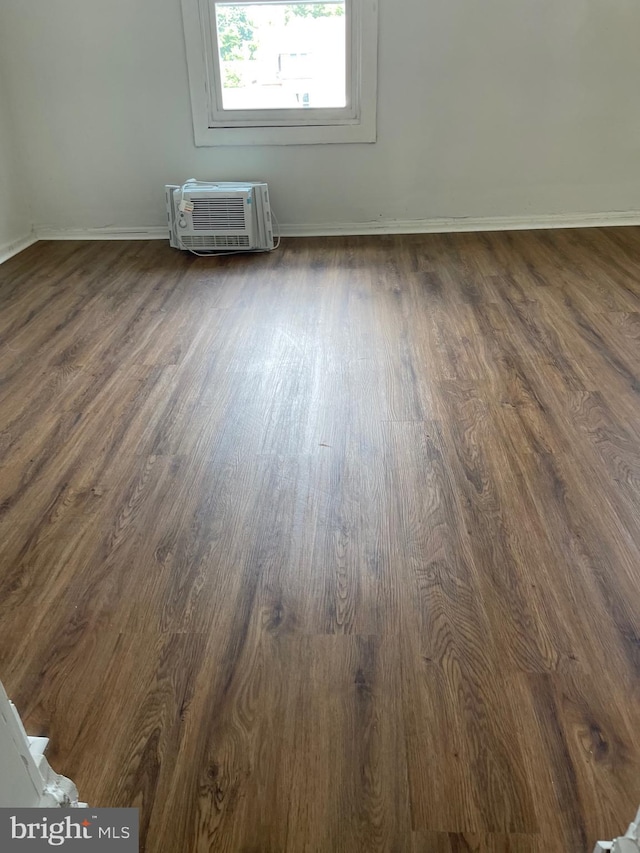 unfurnished room with dark hardwood / wood-style flooring and an AC wall unit