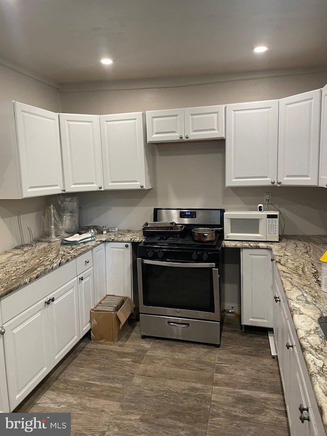 kitchen with white cabinetry, dark hardwood / wood-style floors, stainless steel range with gas cooktop, and light stone counters