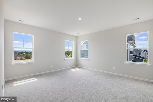 unfurnished room featuring plenty of natural light and carpet