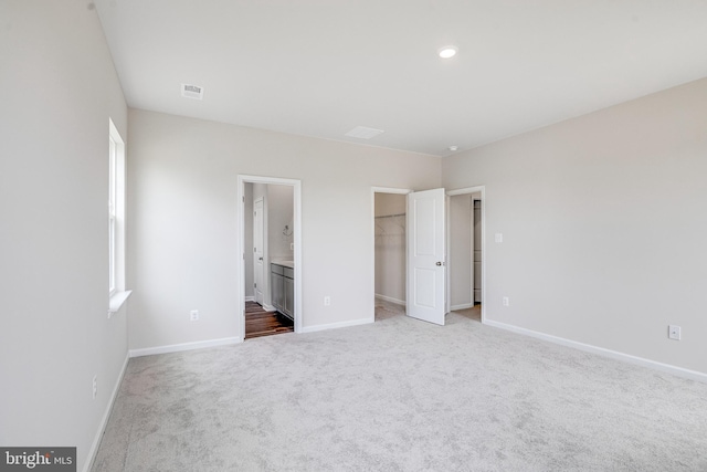 unfurnished bedroom featuring a closet, a spacious closet, carpet, and connected bathroom