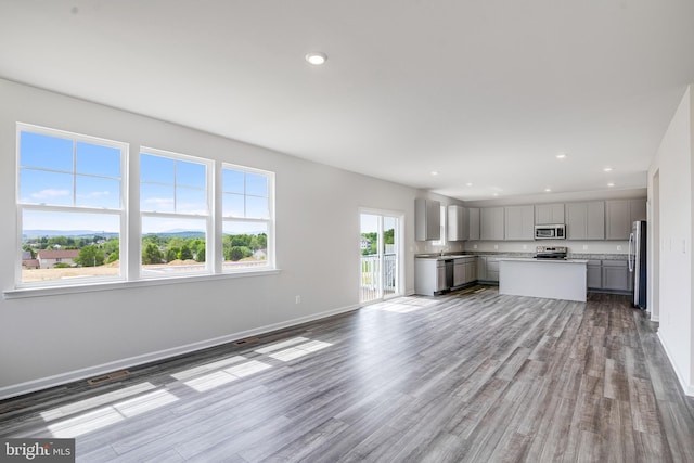 unfurnished living room featuring plenty of natural light and hardwood / wood-style floors