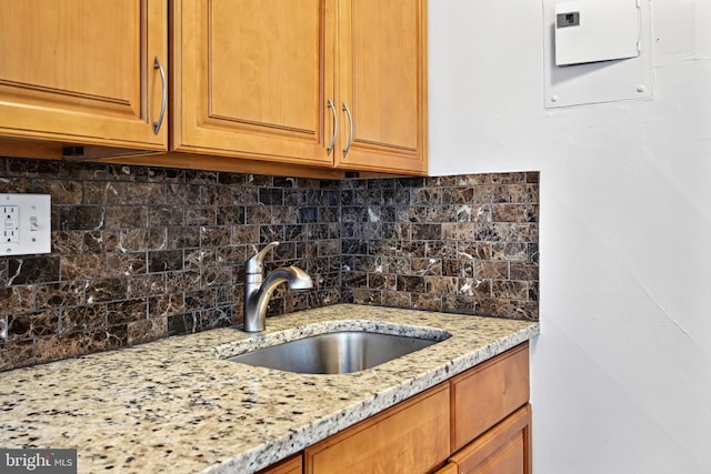 kitchen with light stone countertops, sink, and tasteful backsplash