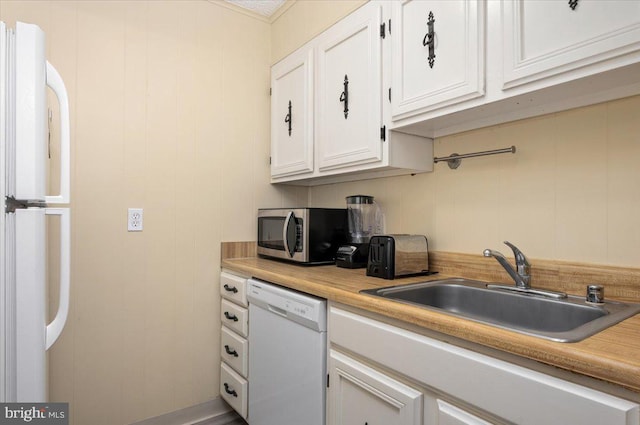 kitchen with white appliances, white cabinets, and sink