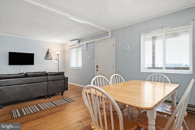 dining area featuring a textured ceiling, light wood-type flooring, and a wall mounted air conditioner