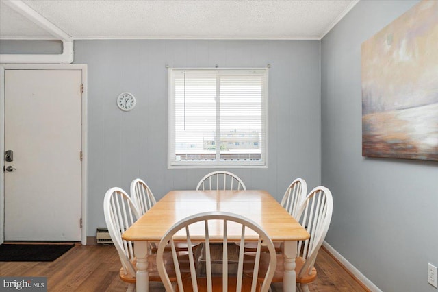 dining space featuring ornamental molding, hardwood / wood-style flooring, and a textured ceiling