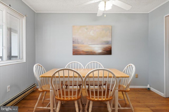 dining space featuring a baseboard heating unit, a textured ceiling, wood-type flooring, and ceiling fan