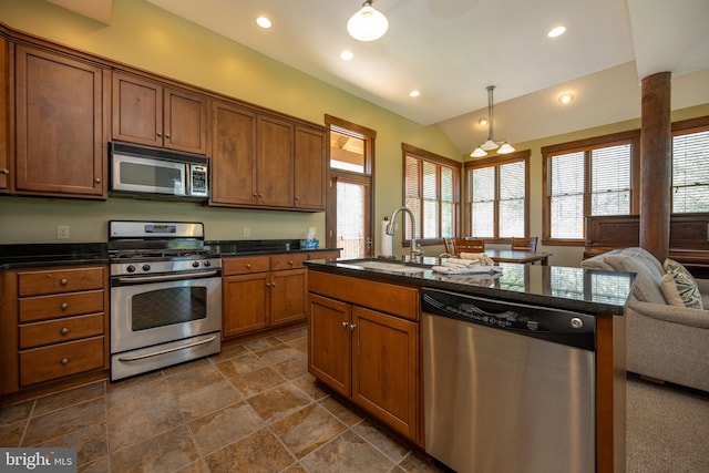 kitchen with lofted ceiling, sink, hanging light fixtures, an island with sink, and stainless steel appliances