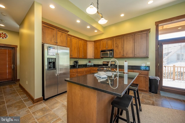 kitchen featuring a breakfast bar, stainless steel appliances, sink, pendant lighting, and a center island with sink