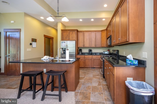 kitchen with hanging light fixtures, a kitchen bar, stainless steel appliances, and a kitchen island with sink