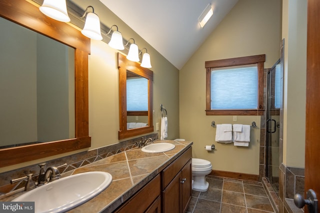 bathroom with vanity, toilet, a shower with door, and vaulted ceiling