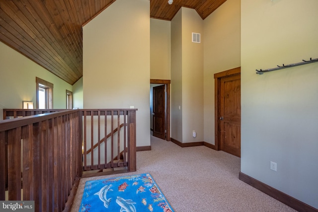 hall with light carpet, high vaulted ceiling, and wood ceiling