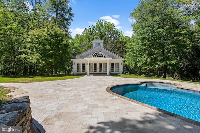 view of pool with an outdoor structure, a patio area, a yard, and french doors