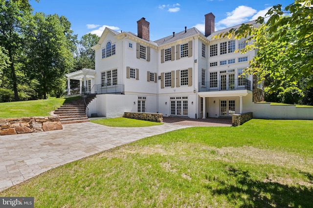 rear view of house featuring a pergola, a yard, a patio, and french doors