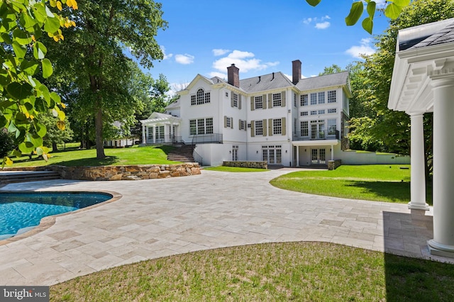 rear view of property featuring a lawn, a patio, and french doors