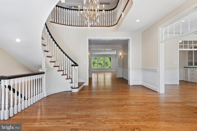 entrance foyer featuring a chandelier, a high ceiling, light hardwood / wood-style floors, and crown molding