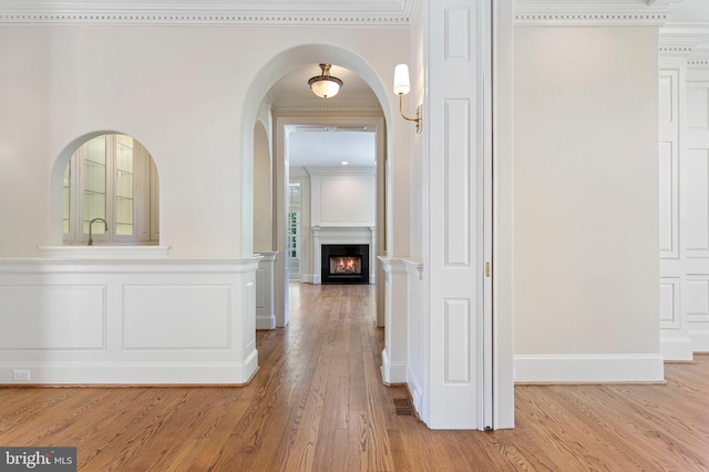 hallway featuring light wood-type flooring and ornamental molding