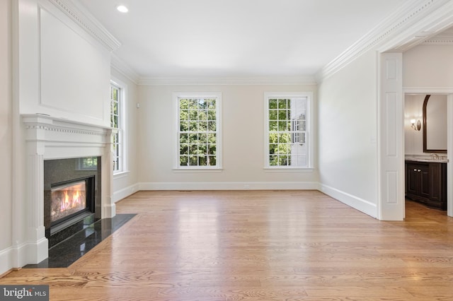 unfurnished living room with a fireplace, a wealth of natural light, light hardwood / wood-style flooring, and ornamental molding