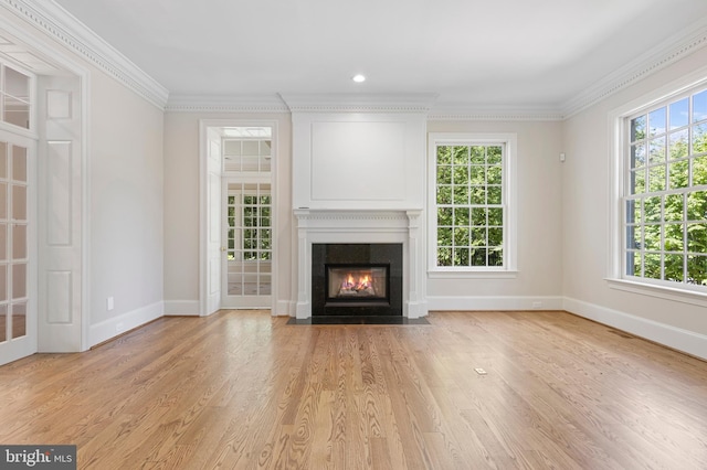 unfurnished living room with light wood-type flooring, crown molding, and a healthy amount of sunlight