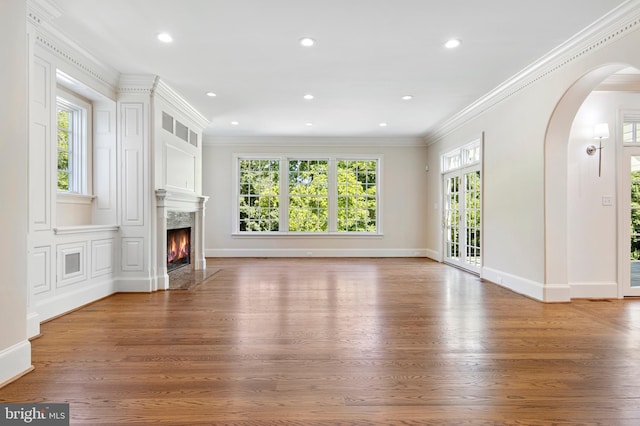 unfurnished living room with hardwood / wood-style floors, ornamental molding, a high end fireplace, and french doors