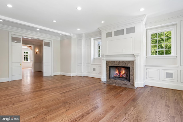 unfurnished living room featuring a high end fireplace, light hardwood / wood-style flooring, and ornamental molding