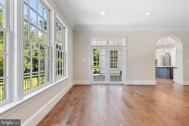 interior space with a chandelier, french doors, ornamental molding, and light wood-type flooring