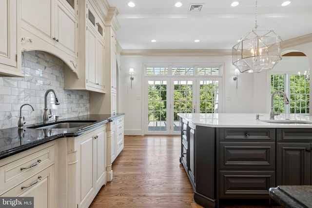 kitchen featuring pendant lighting, crown molding, wood-type flooring, and sink