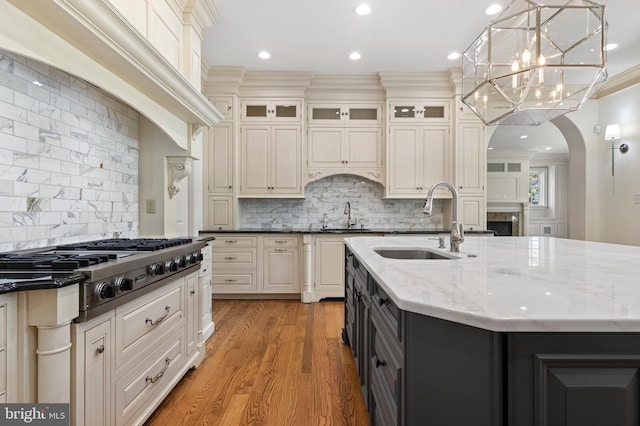 kitchen featuring decorative backsplash, stainless steel gas cooktop, sink, pendant lighting, and light hardwood / wood-style flooring