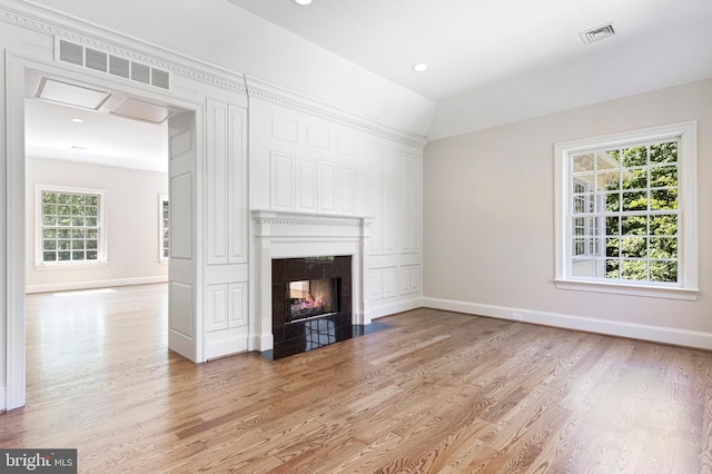 unfurnished living room featuring light hardwood / wood-style floors, vaulted ceiling, and a healthy amount of sunlight