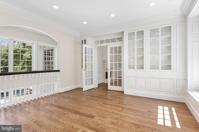 empty room with french doors, light hardwood / wood-style floors, and crown molding