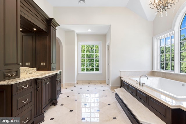 bathroom featuring vanity, tile patterned flooring, a chandelier, lofted ceiling, and a tub