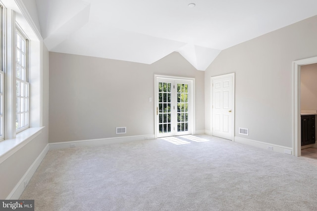 interior space featuring light colored carpet, lofted ceiling, and french doors