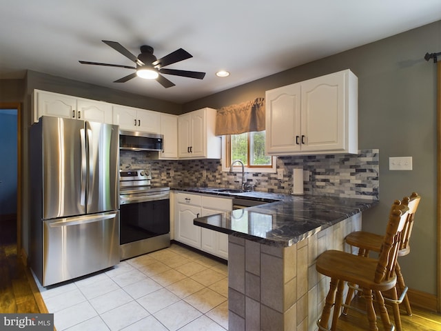 kitchen with ceiling fan, appliances with stainless steel finishes, kitchen peninsula, and white cabinetry