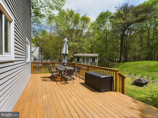 wooden terrace with a lawn and an outdoor fire pit