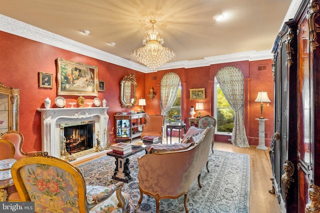 living room featuring a notable chandelier, a premium fireplace, ornamental molding, and light hardwood / wood-style flooring