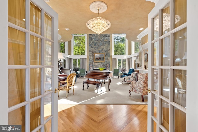 sunroom / solarium featuring french doors, a stone fireplace, and a notable chandelier