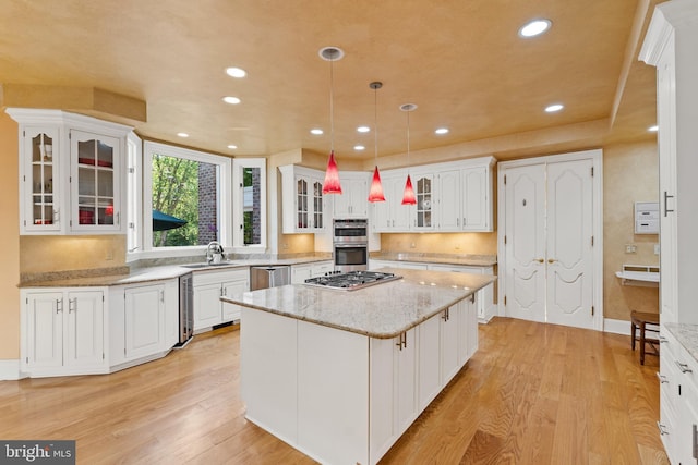 kitchen featuring white cabinetry, light stone counters, pendant lighting, light hardwood / wood-style floors, and a kitchen island