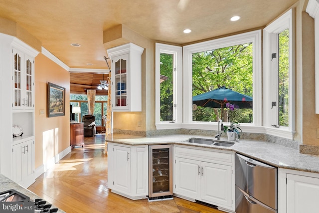 kitchen featuring plenty of natural light, white cabinetry, sink, and wine cooler