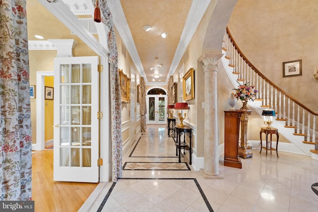 interior space featuring ornate columns, a towering ceiling, light tile patterned floors, and ornamental molding