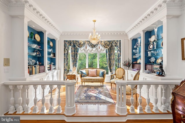 sitting room featuring hardwood / wood-style floors, a chandelier, built in features, and ornamental molding