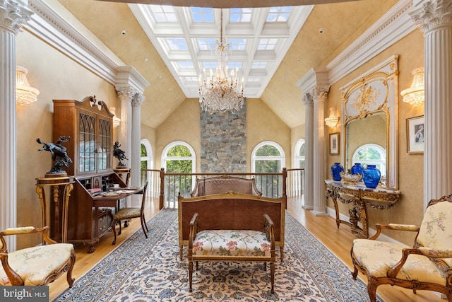 sitting room featuring hardwood / wood-style floors, high vaulted ceiling, ornate columns, and a notable chandelier