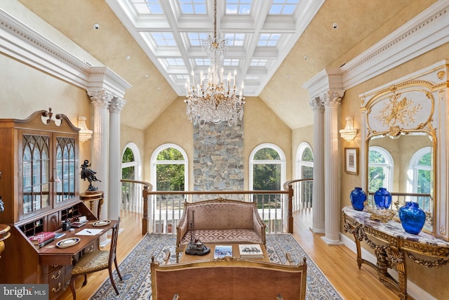 sitting room with an inviting chandelier, light hardwood / wood-style floors, high vaulted ceiling, and ornate columns