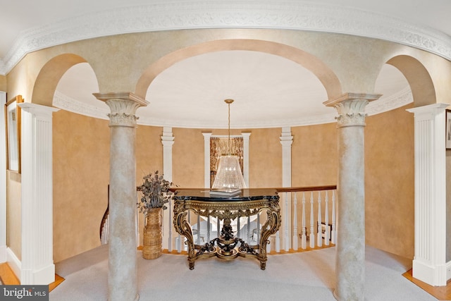 hall featuring decorative columns, crown molding, light colored carpet, and a chandelier