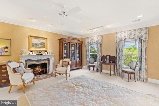 living area featuring ceiling fan, rail lighting, light colored carpet, a fireplace, and ornamental molding