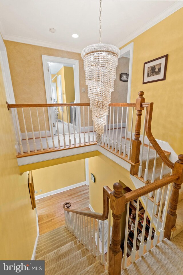 staircase with wood-type flooring, crown molding, and a chandelier